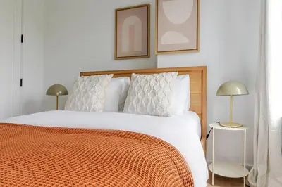 a bedroom with a bed with an orange blanket and two lamps at Blueground South Williamsburg washer nr Domino Park NYC-1866 in Brooklyn