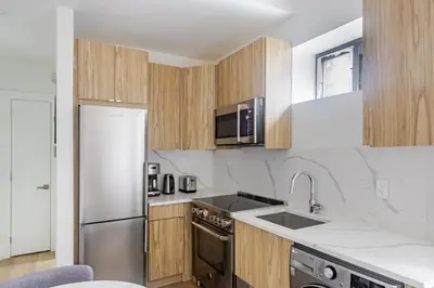 a kitchen with wooden cabinets and a stainless steel refrigerator at Blueground Murray Hill washer nr Bryant Park NYC-1870 in New York