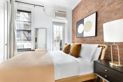 a bedroom with a white bed and a brick wall at Blueground West Village terrace nr Hudson River Park NYC-2123 in New York