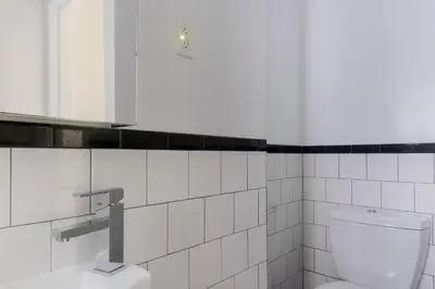 a white tiled bathroom with a toilet and a sink at Blueground West Village view nr Hudson River NYC-1933 in New York
