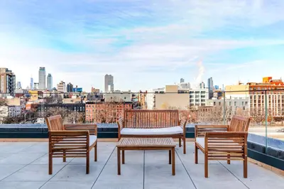 a patio with three chairs and a table on a roof at Blueground Williamsburg rooftop nr Domino Park NYC-2204 in Brooklyn