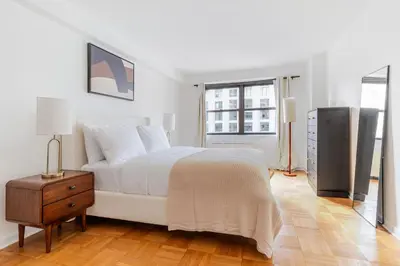 a white bedroom with a bed and a window at Blueground Yorkville pool nr Central Park NYC-2218 in New York