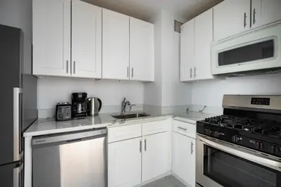 a kitchen with white cabinets and a stove top oven at Blueground Yorkville pool nr Central Park NYC-2218 in New York