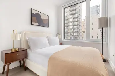 a white bedroom with a bed and a window at Blueground Gramercy Park rooftop nr Flatiron NYC-2203 in New York