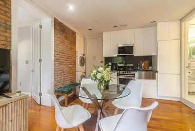a kitchen and dining room with a glass table and white chairs at Suite 24 - East Harlem, Manhattan by Monthier in New York