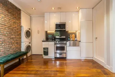 a kitchen with white cabinets and a brick wall at Suite 24 - East Harlem, Manhattan by Monthier in New York