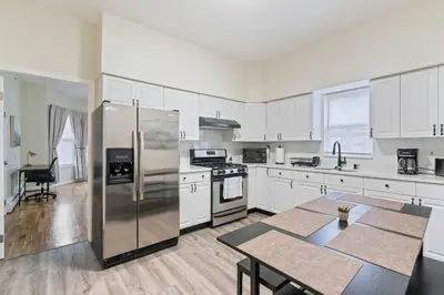 a kitchen with white cabinets and a table and a refrigerator at Spacious 2BR - 15m to Times Square - FREE Parking in North Bergen