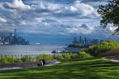 a group of people sitting in a park with a view of the city at Spacious 2BR - 15m to Times Square - FREE Parking in North Bergen