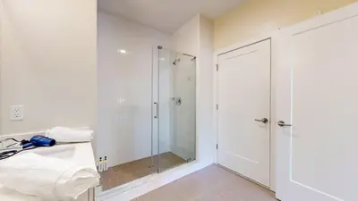 a white bathroom with a shower and a glass door at Modern Comforts Free Gym Access in Stamford
