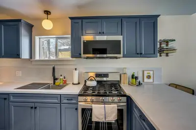 a kitchen with blue cabinets and a stove top oven at Lakefront Escape with Dock! Hudson Valley Home in Hillsdale