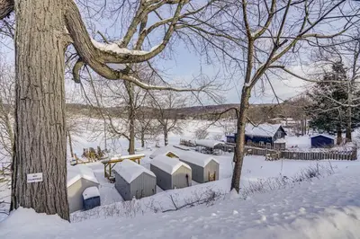 a group of buildings covered in snow next to a tree at Lakefront Escape with Dock! Hudson Valley Home in Hillsdale