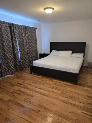 a bedroom with a bed and a wooden floor at Stylish 3BR Retreat Near EWR Airport NYC Hub in Newark