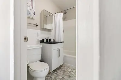 a white bathroom with a toilet and a tub at Landing Stylish 1BD Gym in New Haven