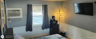 a room with a window with a fan and a television at Windmill Motel Restaurant in Bernardston
