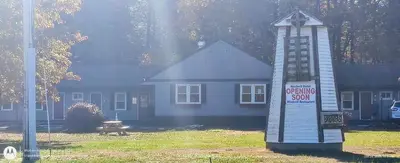 a building with a sign in front of a house at Windmill Motel Restaurant in Bernardston
