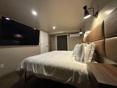 a bedroom with a large white bed and a flat screen tv at The Vault - Hidden Playroom For Couples - Private Hot Tub - Mountain Views - Riverfront in Barryville
