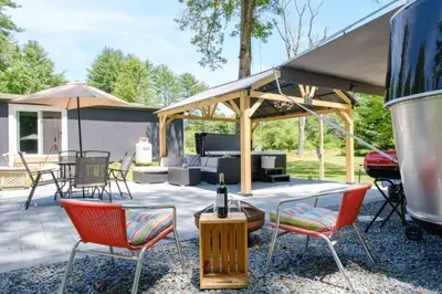 a patio with chairs and a table and a grill at Gilded Cage Escapes - Hidden Playroom For Couples - Private Hot Tub - Mountain Views - Riverfront in Lackawaxen