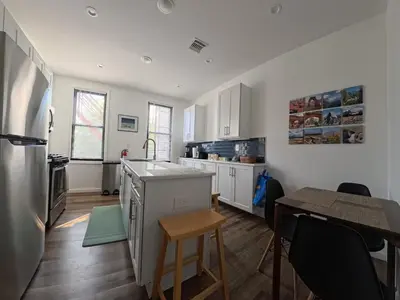 a kitchen with white cabinets and a table and a counter at Duplex 15 mins from Time Square! in West New York
