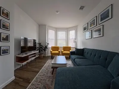 a living room with a blue couch and yellow chairs at Duplex 15 mins from Time Square! in West New York