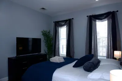 a bedroom with a bed with blue sheets and windows at New York private room 31 in West New York