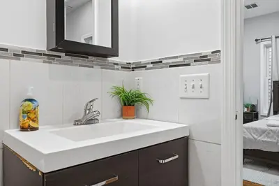 a bathroom with a white sink and a bedroom at Sleeps 19 • 15ft Celings • Near NYC in Jersey City