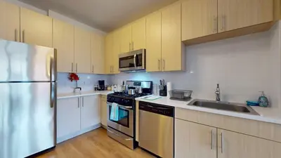 a kitchen with white cabinets and a stainless steel refrigerator at Stylish Home with Free Parking in Stamford