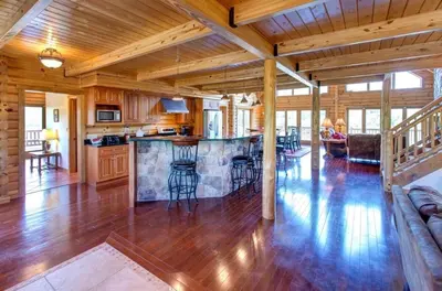 a kitchen and living room with a bar in a house at Waterfront Catskills Log Cabin with Hot Tub & Views in Stamford