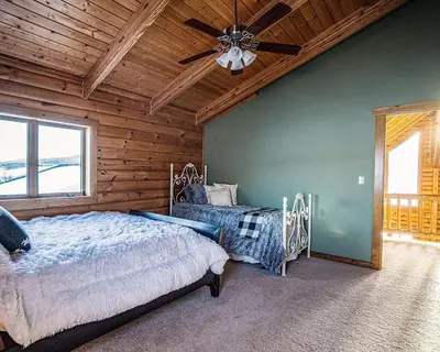 a bedroom with two beds and a ceiling fan at Waterfront Catskills Log Cabin with Hot Tub & Views in Stamford
