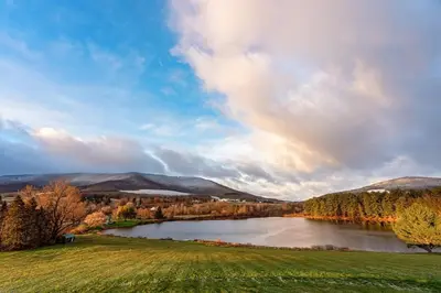 a lake in a field with a rainbow in the sky at Waterfront Catskills Log Cabin with Hot Tub & Views in Stamford