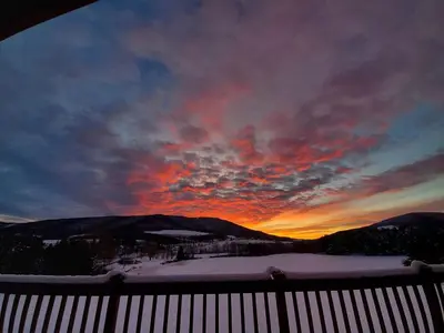 a sunset in the mountains with snow on the ground at Waterfront Catskills Log Cabin with Hot Tub & Views in Stamford