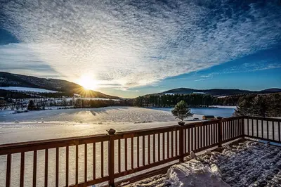 a winter view of a lake with the sun in the sky at Waterfront Catskills Log Cabin with Hot Tub & Views in Stamford