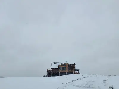 a building sitting on top of a snow covered hill at Waterfront Catskills Log Cabin with Hot Tub & Views in Stamford