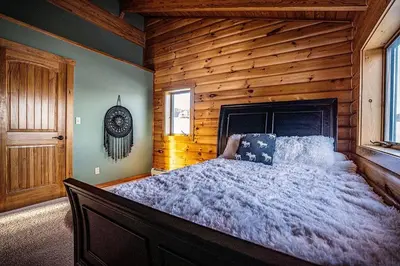 a bedroom with a large bed in a log cabin at Waterfront Catskills Log Cabin with Hot Tub & Views in Stamford