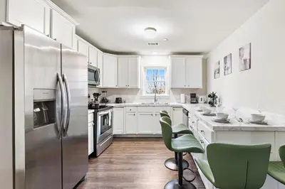a kitchen with white cabinets and a stainless steel refrigerator at Urban Haven XL - NYC & Newark with free parking in Newark