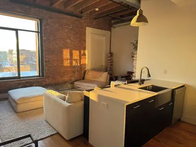 a kitchen with a sink and a living room at Sky-High Sanctuary Penthouse with Panoramic Views in Brooklyn