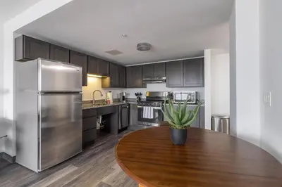 a kitchen with a wooden table and a stainless steel refrigerator at Landing Chic 1BD Pool Game Room in Hartford
