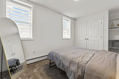 a white bedroom with a bed and two windows at New England Nest - Modern 2BR Home with EV Charger in Shelton