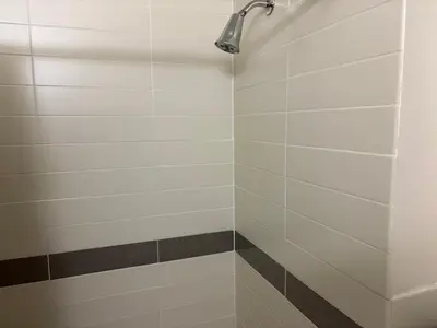 a shower with white tiles and a shower head at Inner City Charm in New York