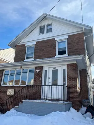 a brick house with a white door in the snow at Cozy guest room 20mins to city in North Bergen