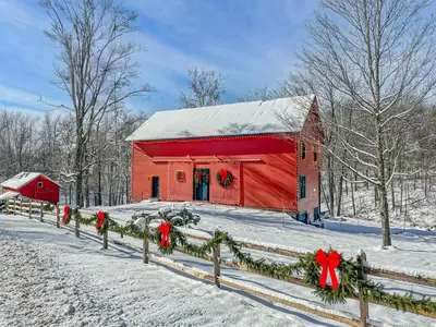a red barn covered in snow with christmas wreaths on it at Modern Barn with Hot Tub, Game Room & Sleeps 14 in High Falls