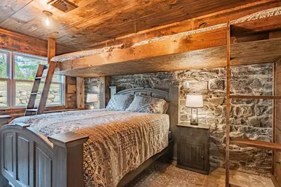 a bedroom with a bed and a stone wall at Modern Barn with Hot Tub, Game Room & Sleeps 14 in High Falls