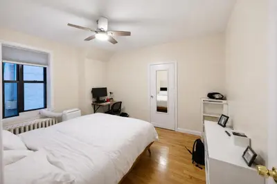 a white bedroom with a bed and a ceiling fan at Bright & Modern Apartment Near Subway & Columbia in New York