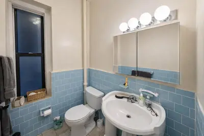 a blue tiled bathroom with a toilet and a sink at Bright & Modern Apartment Near Subway & Columbia in New York