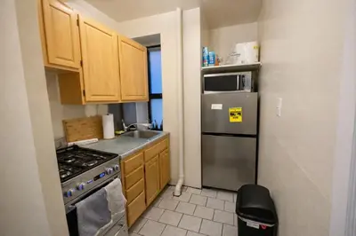 a kitchen with wooden cabinets and a stainless steel refrigerator at Bright & Modern Apartment Near Subway & Columbia in New York
