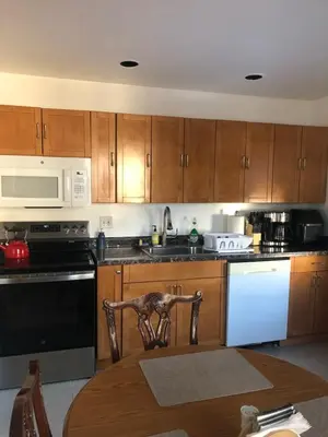 a kitchen with wooden cabinets and white appliances at Comfort house with two bed room in Greenwich