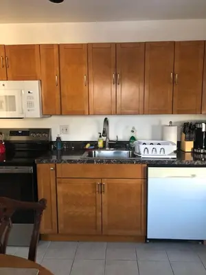 a kitchen with wooden cabinets and a white dishwasher at Comfort house with two bed room in Greenwich