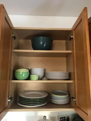 a kitchen cabinet with plates and bowls in it at Comfort house with two bed room in Greenwich