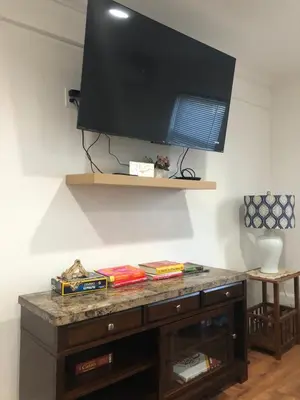 a flat screen tv on a wall with a wooden dresser at Comfort house with two bed room in Greenwich