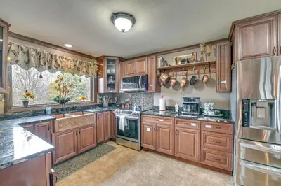a kitchen with wooden cabinets and stainless steel appliances at Beautiful and Unique Farmhouse 15 Mi to Saratoga in Argyle