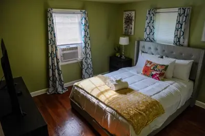 a bedroom with a large bed and two windows at Pet Friendly 3BR New Britain Home with King Bed Near Hartford Sleeps 8 in New Britain